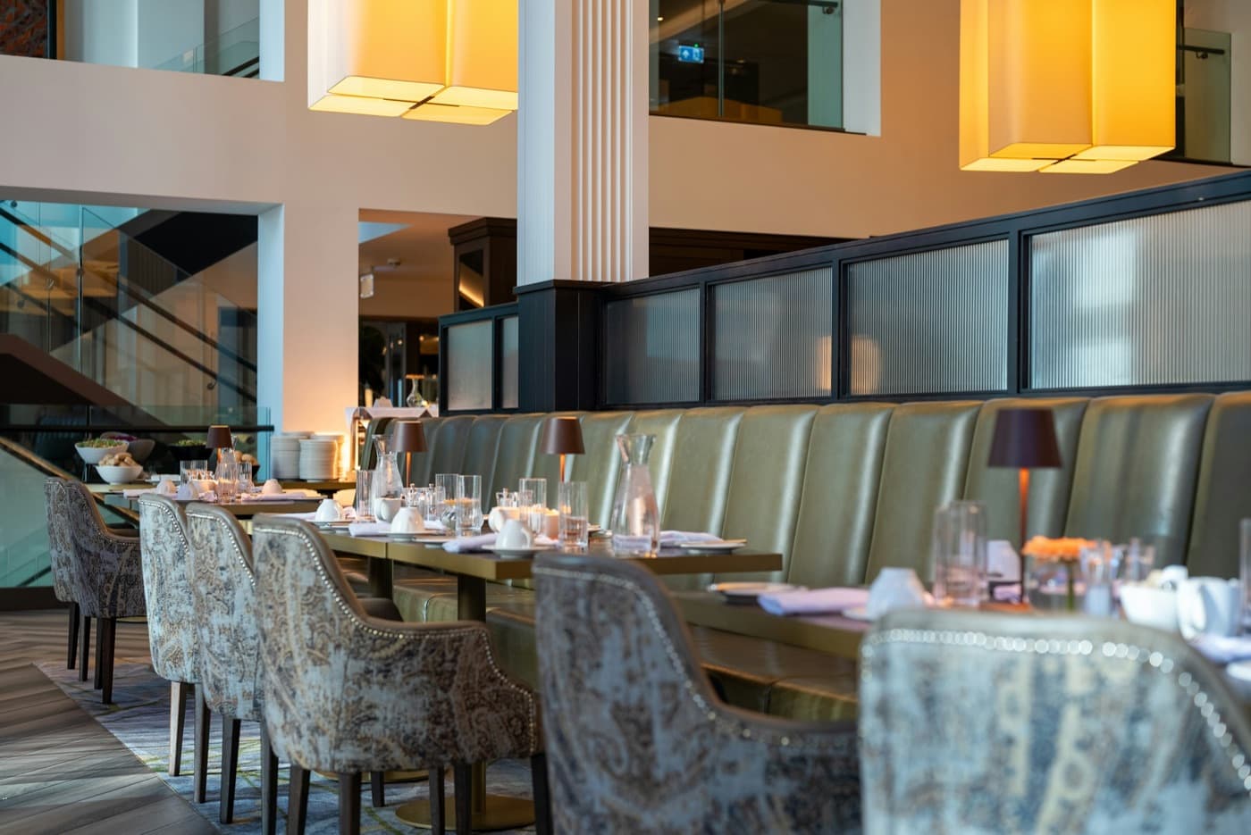 A dining room seen from the entrance, tables set and banquettes along one wall