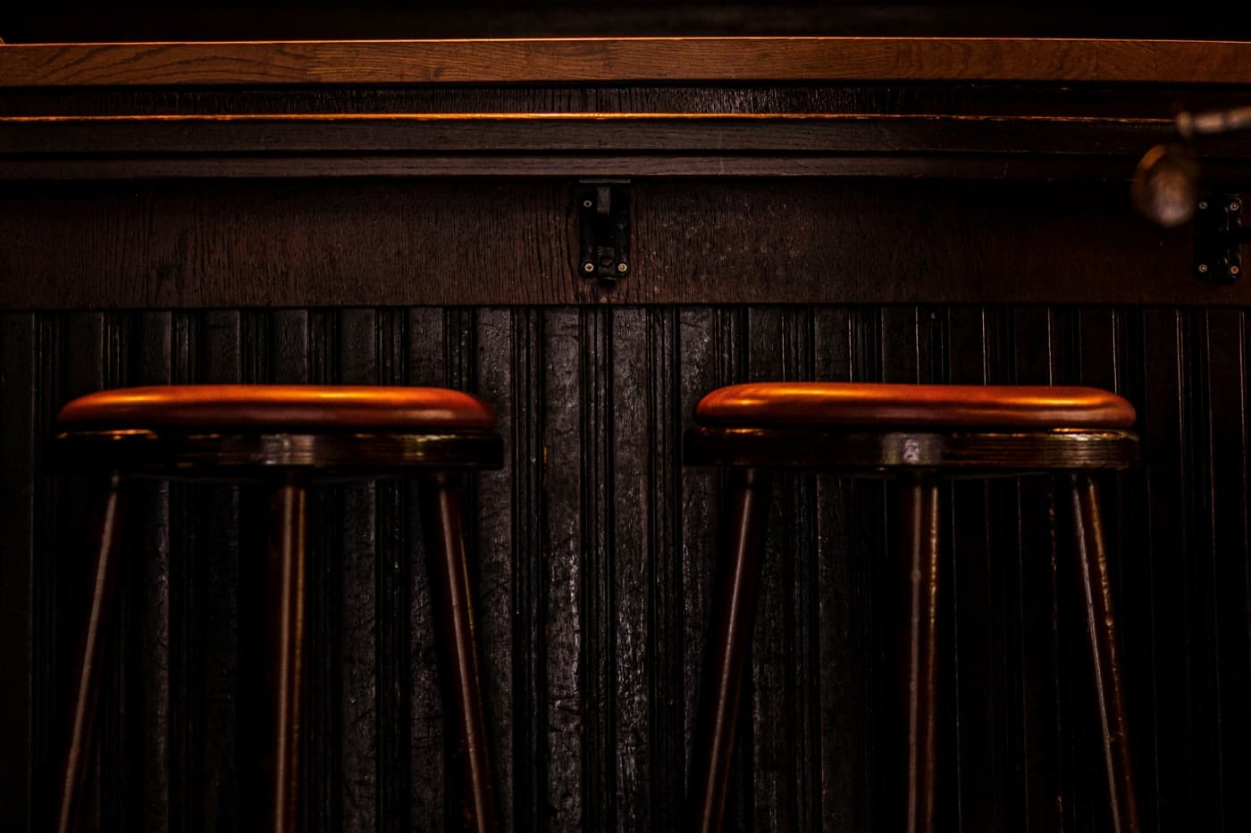 A long counter with stools along it under a pressed-tin ceiling