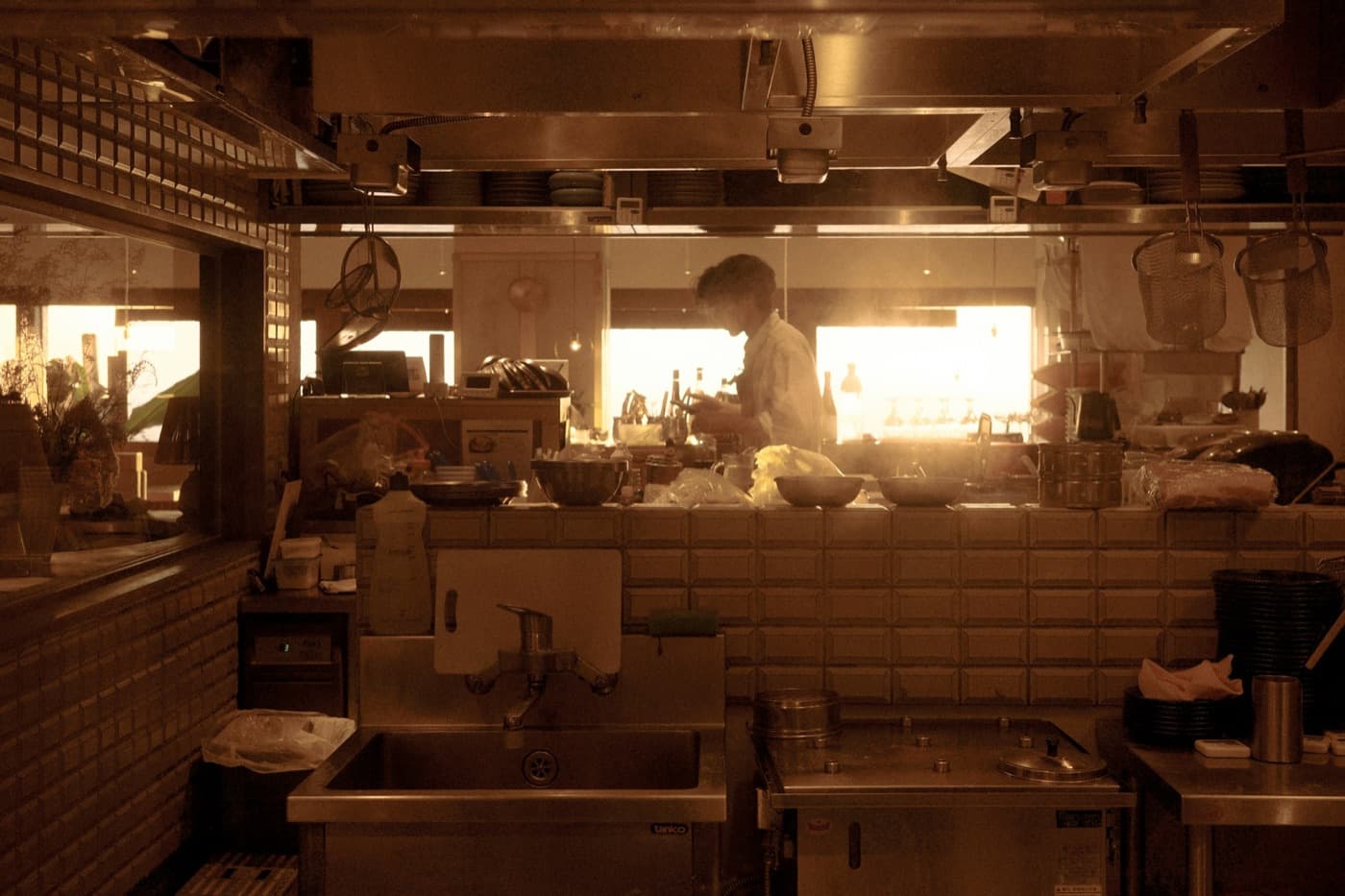 A cook working at the pass in a bright kitchen, seen from the counter