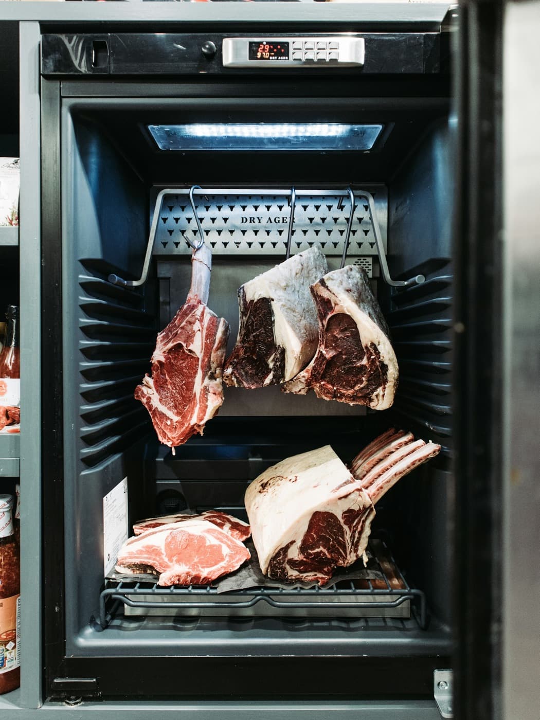 Cuts of beef hanging in a dry-aging cabinet