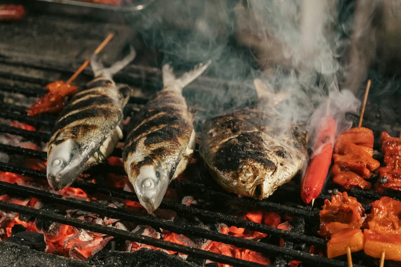 Whole fish over an open grill, flames beneath the bars